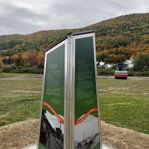 Borne patrimoniale avec cadres en aluminium et panneaux verts, installée sur une base de béton.